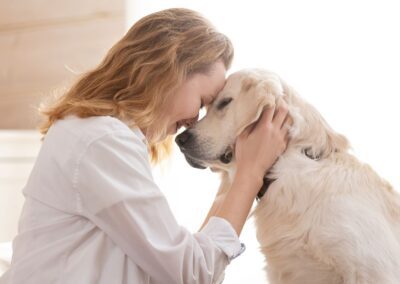 Woman cuddling golden dog indoors