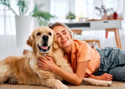 A woman hugging a dog while lying on the ground